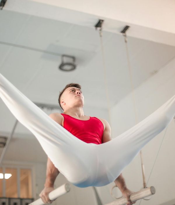 Man performing a controlled strength exercise in a dark, minimalist gym.